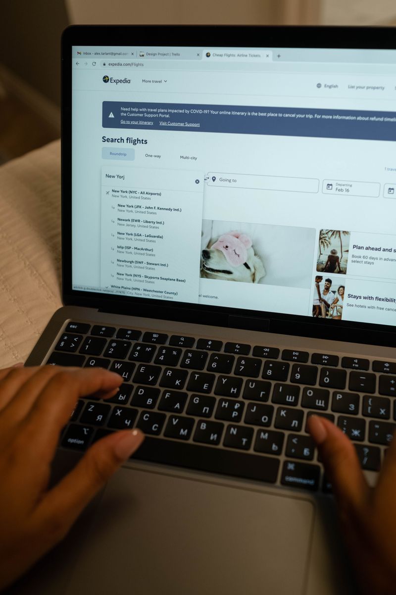 Person typing on laptop, searching flight details indoors